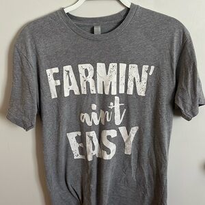 Light gray t shirt, “farmin’ ain’t easy”